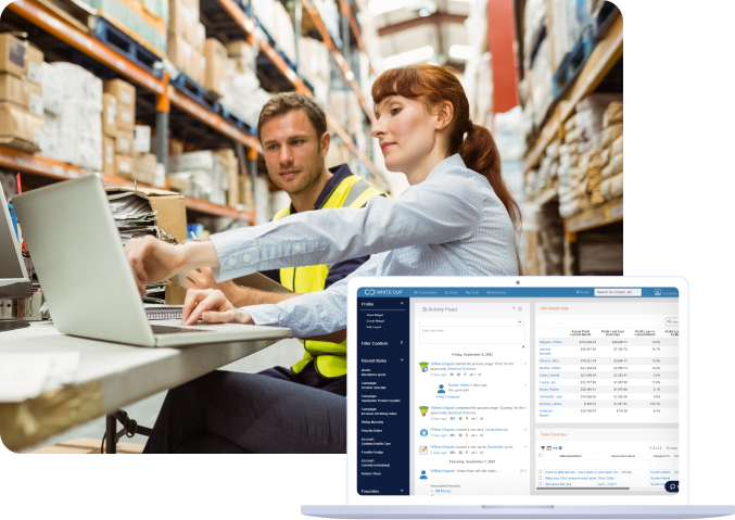 warehouse workers using a laptop to review White Cup CRM dashboard, showcasing sales and customer insights on a screen